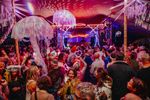 Crowded dance tent decorated with illuminated jellyfish, mirrored balls and colourful lighting. Photograph by Coal Poet Media.