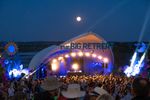 A crowd gathered in front of The Big Retreat main stage beneath the moon at night.