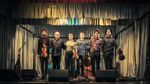 Members of Frigg stand together on stage holding fiddles after a performance in Stenness. Photograph: Lieve Boussauw.