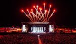 Crowd watching a night-time performance at Victorious Festival main stage with bright red fireworks overhead.