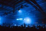 Wide view across a large festival crowd beneath blue stage lighting.