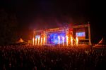 Large night-time crowd facing the outdoor Teddy Rocks stage as flame effects rise across the front.
