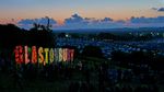 The Glastonbury Festival sign overlooking the campsite at sunset. Photograph by jaswooduk, licensed CC BY 2.0.