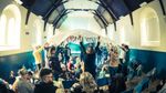 Adults lift a white fabric canopy above children during a Dragon Song Productions family event. Photograph: Lieve Boussauw.