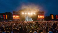 An image of Tramlines festival, looking from a packed crowd to the main stage filled with lights.