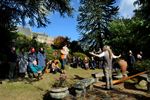 A storyteller addressing a seated and standing audience in a garden.
