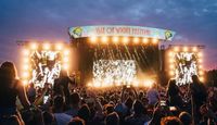 Dusk image of the main stage at the Isle of Wight Festival, large crowd in the foreground.