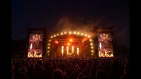 Bloodstock Festival, view of the stage at night, flames and lights with crowd in silhouette.