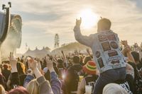 View from the crowd at Download festival, person on shoulders of a fellow rocker giving the horns hand gesture.