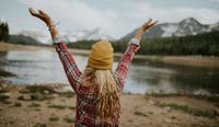 Woman lifting up her arms towards nature, with the feeling of freedom.