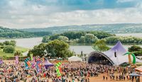 View down to Chew Valley Lake with Valley Fest Festival stage on the shoreline with crowd.