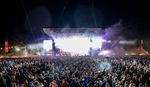 Big Feastival main stage in bright white light with large crowd in the foreground at night.