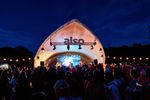 A crowd watching a live performance beneath the illuminated ALSO main-stage canopy at night.