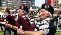 Men playing the bagpipes in traditional clothes.