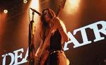 Bass guitarist performing under orange stage lighting at Sound City Festival.