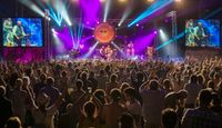 Music performance on the main stage at Wickham Festival with large crowd in the foreground and colourful stage lights filling the stage.