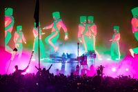 Wilderness festival performance photo showing person in chain-mail suit with electricity sparks coming out from head and hands.