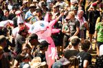 Costumed festivalgoers gather around a large pink inflatable character in a daytime crowd at 2000trees Festival. Photograph by Carla Mundy.