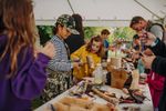 Children and adults making objects from wood and craft materials around a table beneath a marquee. Photograph by Nathan Roach.