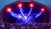 Wychwood festival main stage at night filled with light with crowd in the foreground.