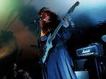 Guitarist and vocalist performing beneath coloured venue lighting.