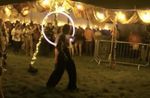 A performer framed by an illuminated hoop beneath a decorated festival tent at night at Moovin Festival.