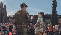 Street performer at Edinburgh Fringe Festival interacting with a young audience member.