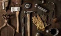 Hand tools and gloves on a wooden table.