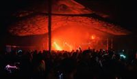 Night scene at Mucky Weekender Festival under a marquee with performers on a brightly lit stage.