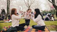 Child and two adults on a picnic blanket.