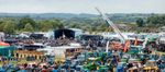 Wide view across Dorset Tractor Fest with the music stage, festival crowd and rows of tractors at Turnpike Showground.