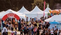 Outside view of HowTheLightGetsIn Festival location, showing marquees and crowd mingling.