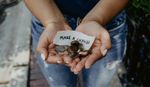 Person holding their hands out with coins and a note which says 'make a change'.