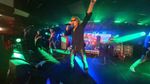 A rock singer wearing sunglasses performing with a microphone under green and blue stage lighting.