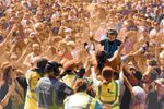 A young festivalgoer wearing ear defenders is carried above a dense daytime crowd at 2000trees Festival. Photograph by Gareth Bull.